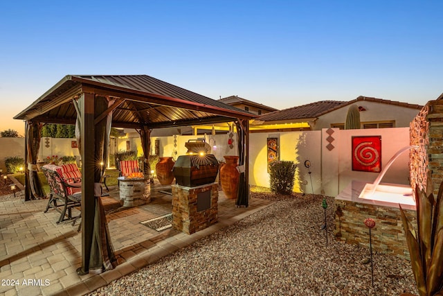 patio terrace at dusk featuring a gazebo and grilling area