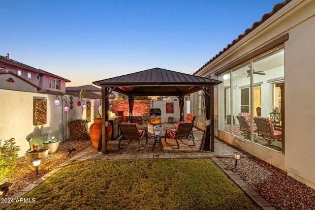 patio terrace at dusk featuring a gazebo and a yard