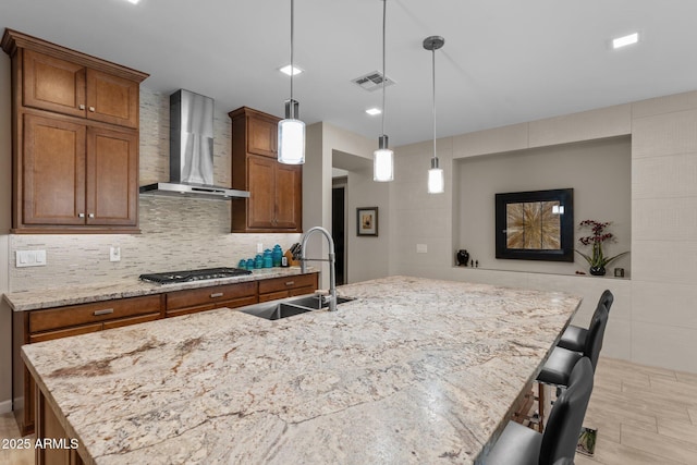 4093 Miners Gulch Way, Wickenburg, AZ 85390 - kitchen with a sink, stainless steel gas stovetop, visible vents, wall chimney range hood, and brown cabinets
