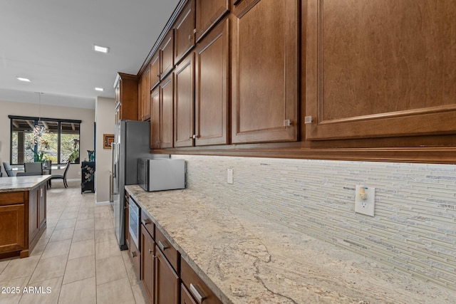 4093 Miners Gulch Way, Wickenburg, AZ 85390 - kitchen featuring baseboards, light stone counters, hanging light fixtures, backsplash, and light tile patterned floors