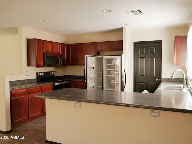 43241 W Kristal Ln, Maricopa, AZ 85138 - kitchen with stainless steel microwave, black electric range, freestanding refrigerator, a sink, and a peninsula