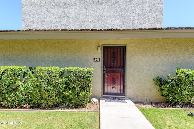 view of exterior entry featuring a yard