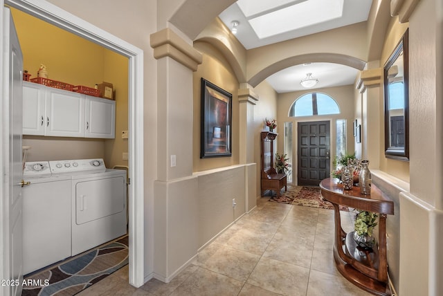 foyer featuring a skylight, arched walkways, separate washer and dryer, and light tile patterned flooring