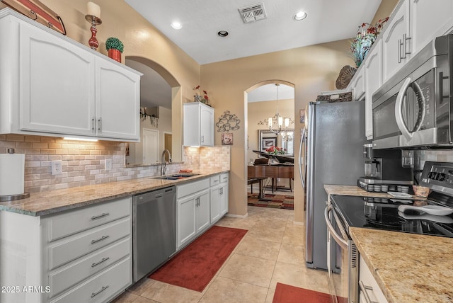 kitchen with arched walkways, stainless steel appliances, a sink, visible vents, and white cabinets