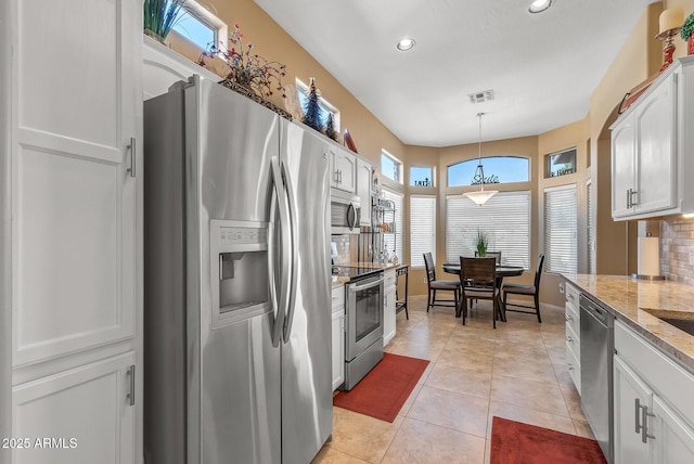 kitchen with light stone counters, visible vents, white cabinetry, hanging light fixtures, and appliances with stainless steel finishes