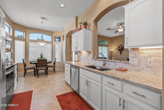 kitchen featuring appliances with stainless steel finishes, a sink, white cabinetry, and decorative light fixtures