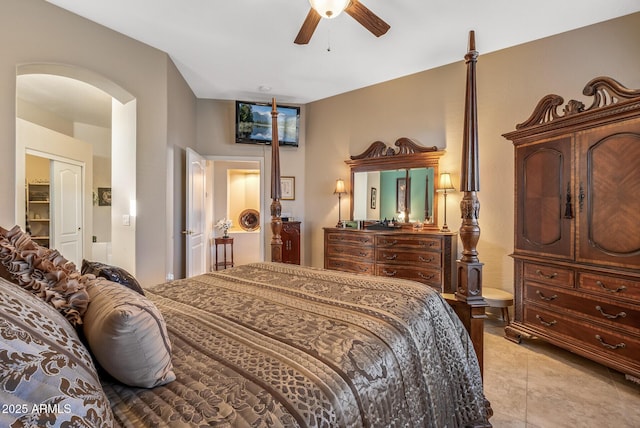 bedroom with arched walkways, light tile patterned floors, and a ceiling fan