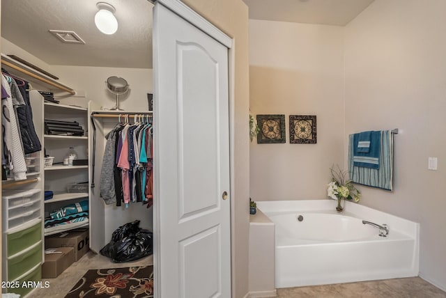 bathroom with tile patterned floors, visible vents, a spacious closet, and a bath