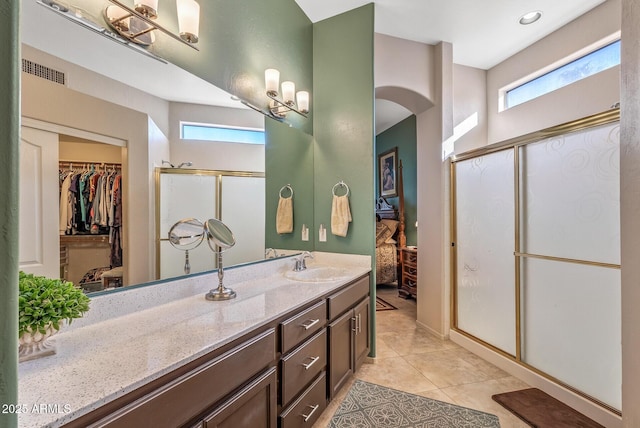 bathroom featuring visible vents, a spacious closet, a stall shower, vanity, and tile patterned floors