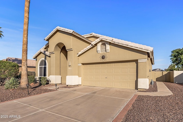 view of front of house featuring a garage, concrete driveway, a tile roof, fence, and stucco siding