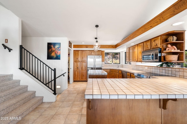 128 N French Dr, Prescott, AZ 86303 - kitchen with stainless steel appliances, tile countertops, open shelves, brown cabinetry, and a peninsula