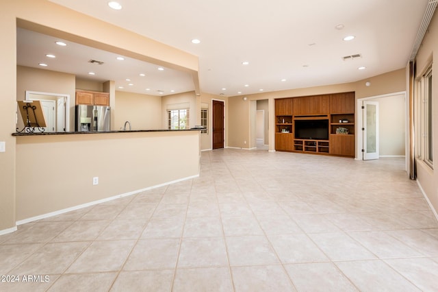 unfurnished living room featuring light tile patterned floors and built in shelves