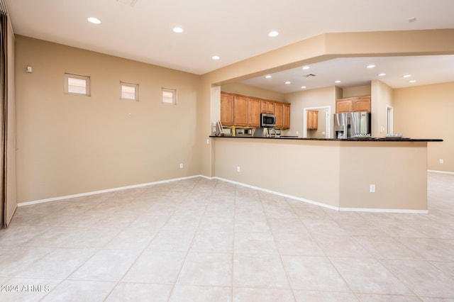 interior space featuring light tile patterned floors, kitchen peninsula, and appliances with stainless steel finishes