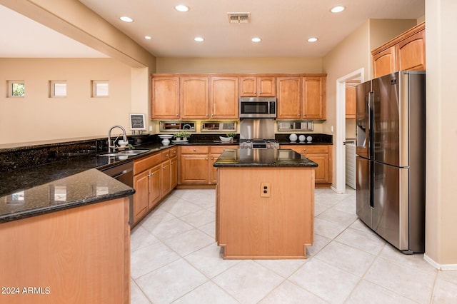 kitchen with stainless steel appliances, sink, a kitchen island, and dark stone countertops