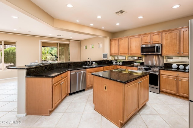 kitchen with a kitchen island, sink, dark stone countertops, kitchen peninsula, and stainless steel appliances