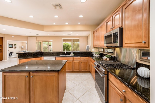 kitchen with appliances with stainless steel finishes, a center island, dark stone countertops, and kitchen peninsula