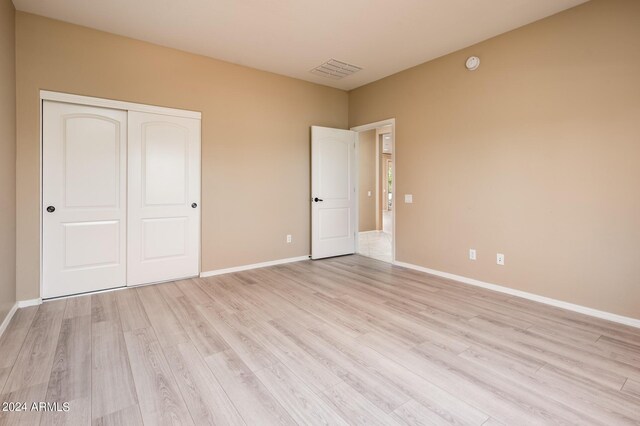 unfurnished bedroom with light hardwood / wood-style floors and a closet