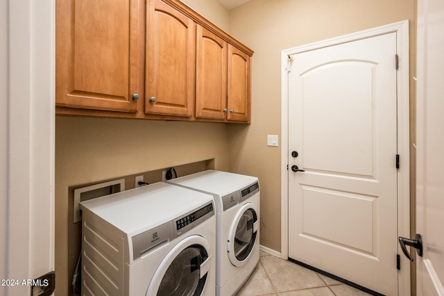 clothes washing area with independent washer and dryer, cabinets, and light tile patterned flooring