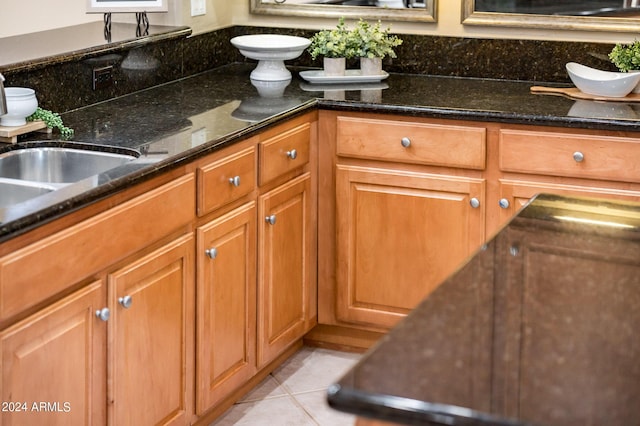 kitchen with dark stone counters, sink, and light tile patterned floors