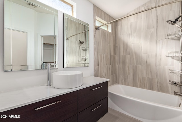 bathroom with tiled shower / bath, vanity, lofted ceiling, and tile patterned flooring