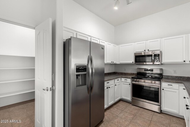 kitchen featuring white cabinetry, light tile patterned floors, dark countertops, and appliances with stainless steel finishes