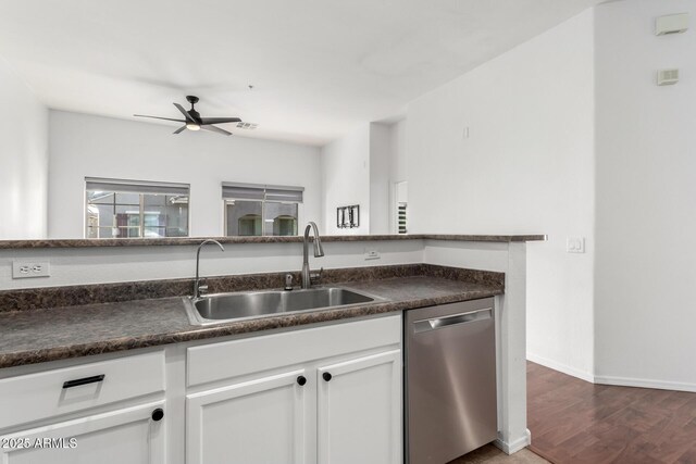 kitchen with a sink, a ceiling fan, white cabinetry, stainless steel dishwasher, and dark countertops