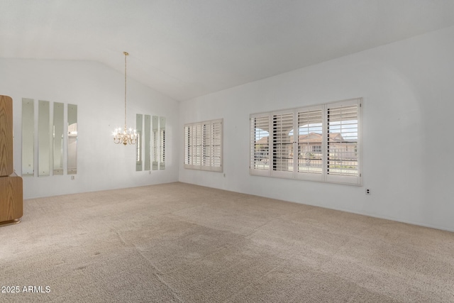 carpeted spare room featuring an inviting chandelier and vaulted ceiling