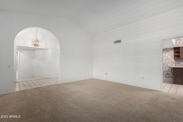 unfurnished room featuring light carpet, a chandelier, and vaulted ceiling