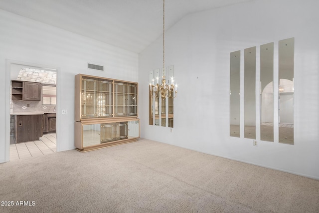 interior space with light colored carpet, high vaulted ceiling, and a chandelier