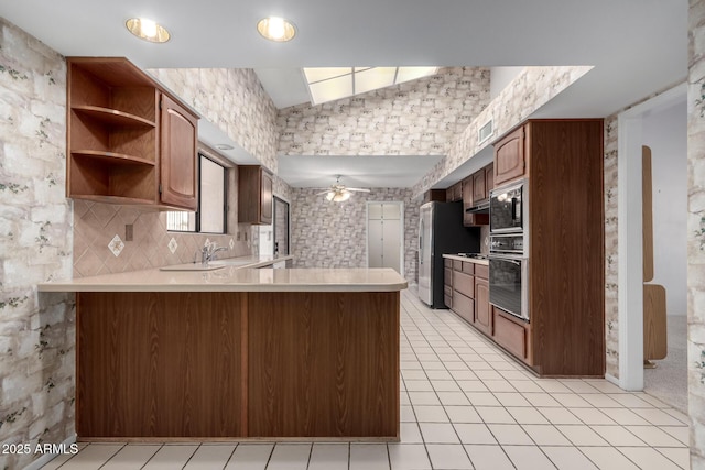 kitchen featuring kitchen peninsula, decorative backsplash, wall oven, built in microwave, and ceiling fan