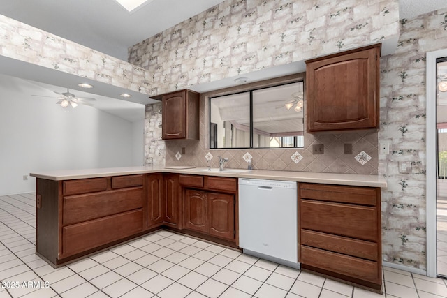 kitchen featuring dishwasher, backsplash, sink, light tile patterned flooring, and kitchen peninsula