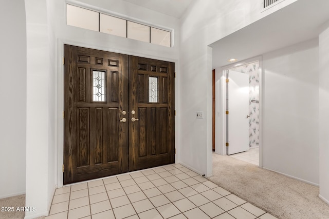 carpeted entryway featuring a towering ceiling