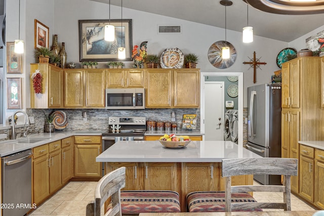 kitchen with sink, a kitchen breakfast bar, backsplash, vaulted ceiling, and appliances with stainless steel finishes