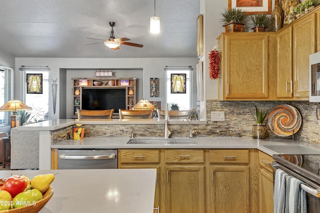 kitchen featuring sink, decorative backsplash, ceiling fan, appliances with stainless steel finishes, and kitchen peninsula