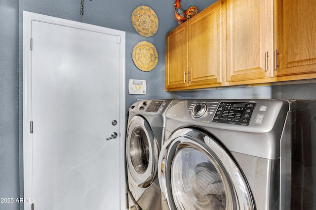 clothes washing area featuring cabinets and washer and clothes dryer