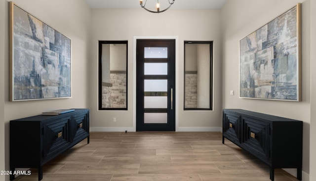 entrance foyer with a chandelier, light wood-type flooring, and baseboards