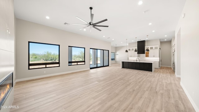 unfurnished living room with light wood finished floors, a sink, a ceiling fan, and recessed lighting