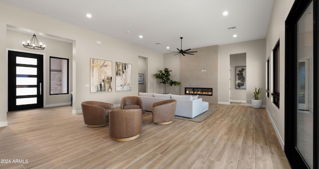 living area with recessed lighting, ceiling fan with notable chandelier, visible vents, light wood-type flooring, and a tiled fireplace