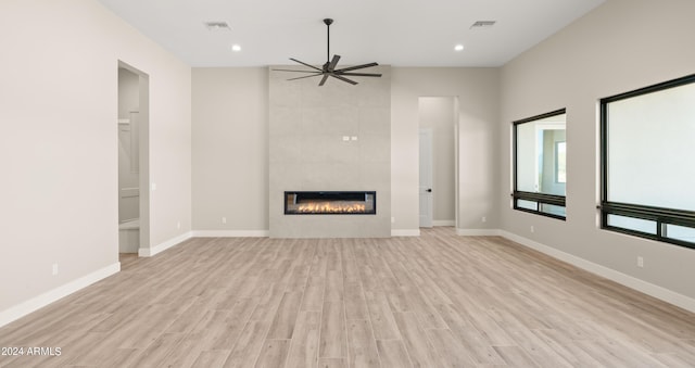 unfurnished living room featuring visible vents, a tiled fireplace, light wood-style floors, ceiling fan, and baseboards