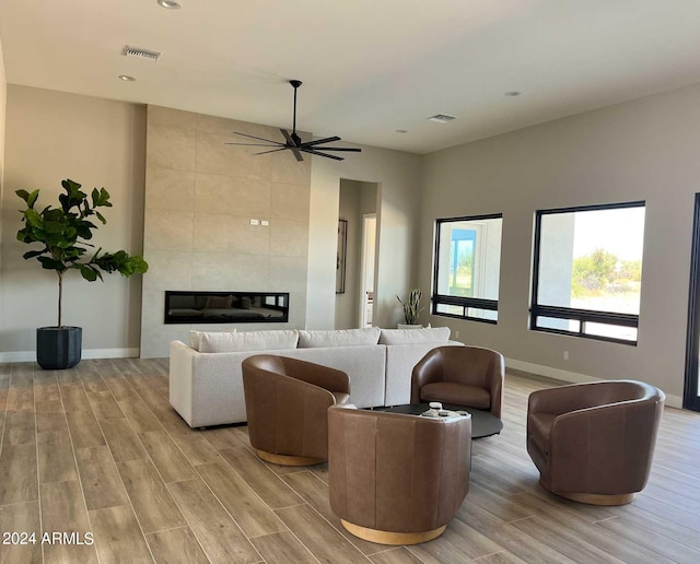 living area featuring light wood-style floors, a tile fireplace, visible vents, and baseboards