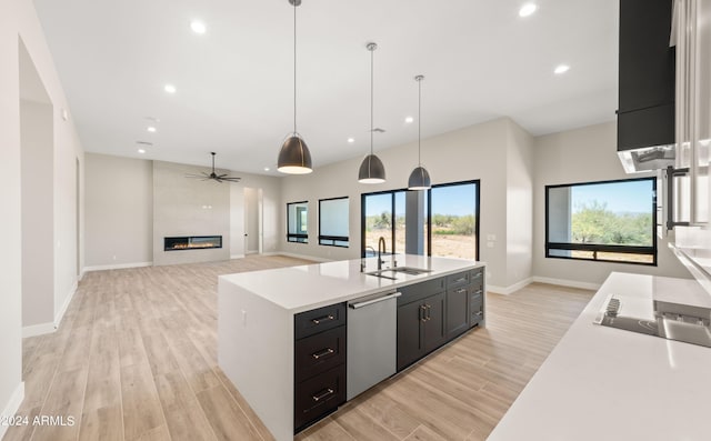 kitchen with a sink, open floor plan, light countertops, dishwasher, and pendant lighting