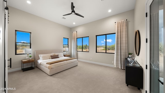 bedroom with light carpet, a barn door, multiple windows, and baseboards