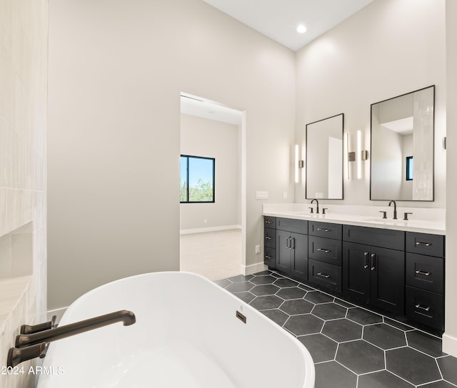 bathroom with double vanity, a soaking tub, a sink, and tile patterned floors