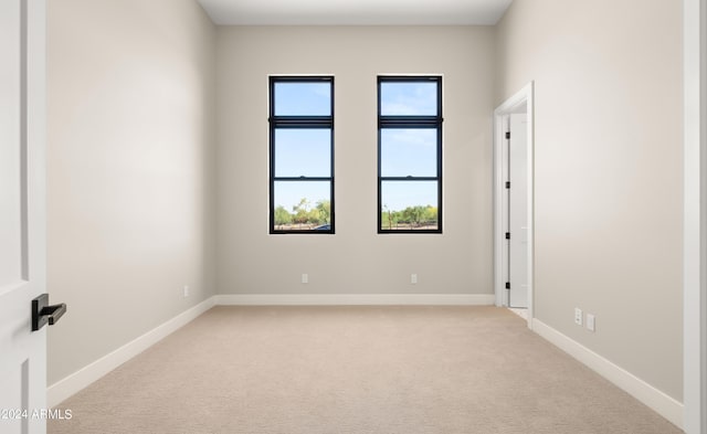 unfurnished room with light carpet and baseboards