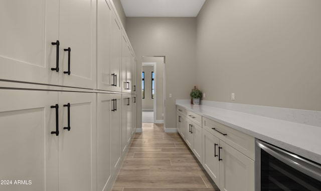 bar featuring wine cooler, light wood-type flooring, and baseboards