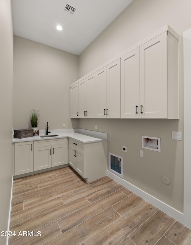 laundry area featuring washer hookup, visible vents, cabinet space, light wood-style flooring, and a sink