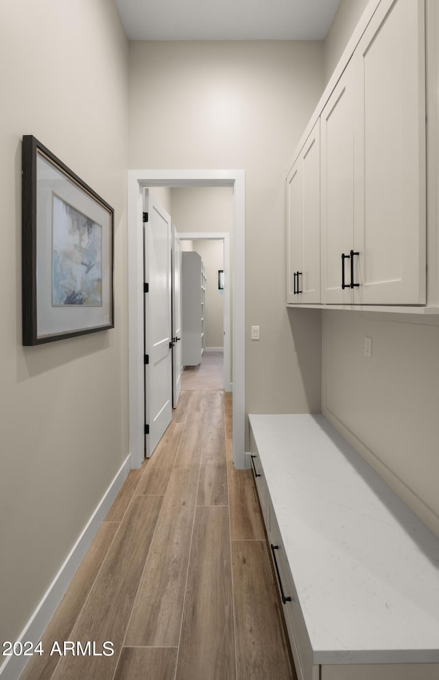 corridor featuring light wood finished floors and baseboards