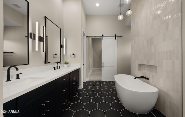 full bath featuring tile patterned flooring, a sink, visible vents, a freestanding bath, and double vanity