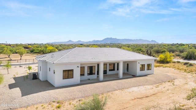 view of front facade with a tile roof, fence, cooling unit, a mountain view, and stucco siding