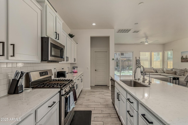 2716 S Chatsworth, Mesa, AZ 85209 - kitchen with stainless steel appliances, decorative backsplash, white cabinets, a ceiling fan, and light wood-type flooring